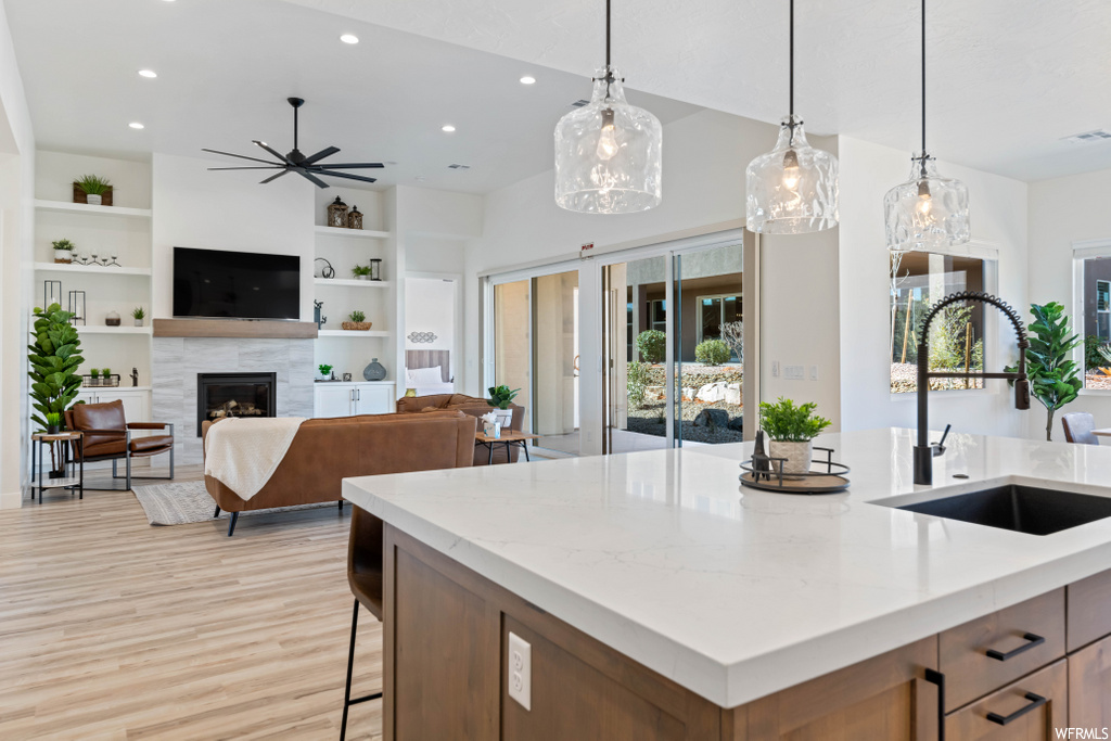 kitchen with natural light, a fireplace, TV, light parquet floors, light countertops, pendant lighting, and a center island with sink