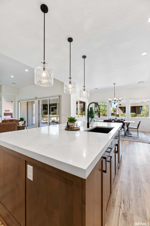 kitchen featuring natural light, pendant lighting, a center island with sink, light countertops, and light hardwood flooring