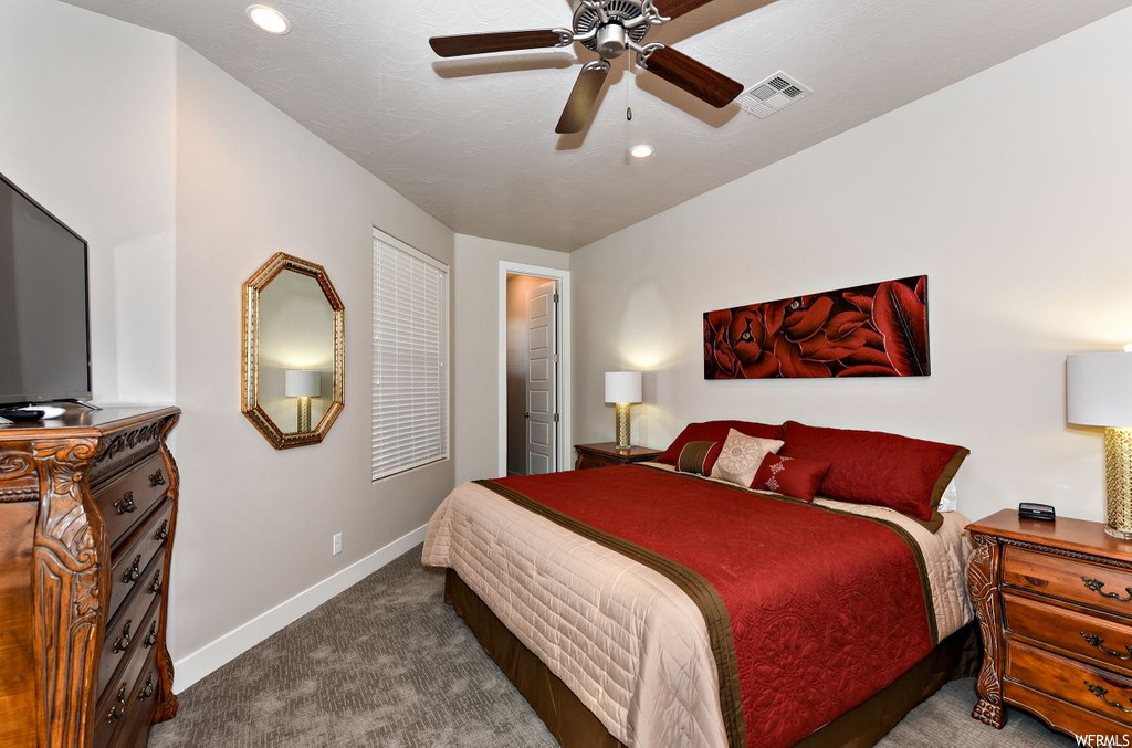 carpeted bedroom with a ceiling fan and TV