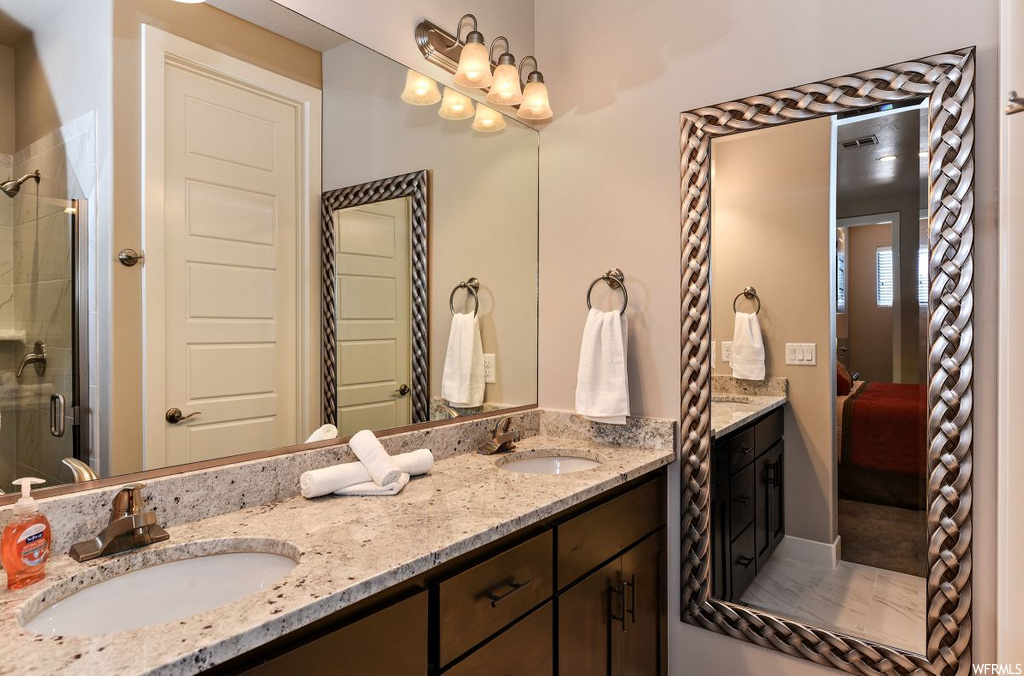 bathroom with mirror, shower with shower door, and his and hers vanity