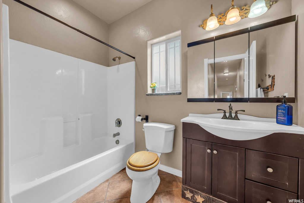 Full bathroom with tile flooring, natural light, toilet, mirror, vanity, and shower / washtub combination