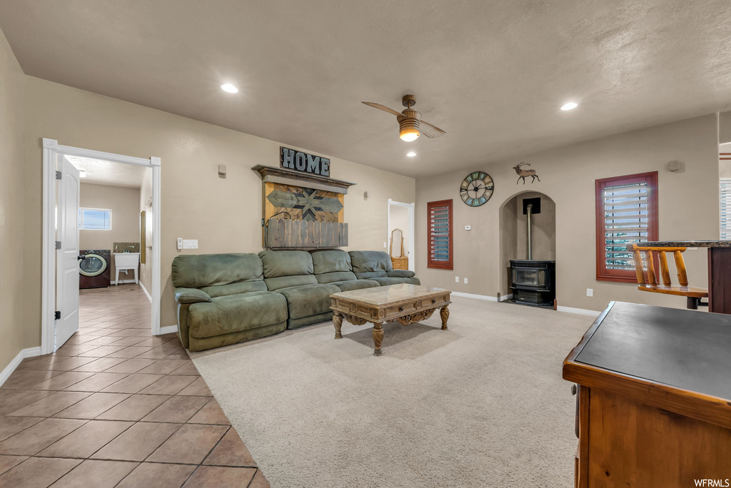 Tiled living room featuring a ceiling fan and natural light