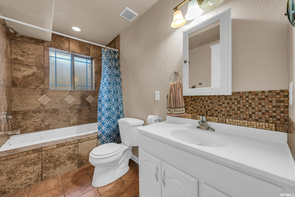 Full bathroom with tile flooring, shower / bathtub combination, toilet, dual mirrors, shower curtain, and vanity