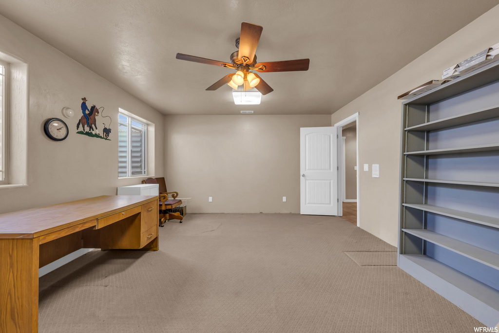 Office space featuring a ceiling fan, carpet, and natural light