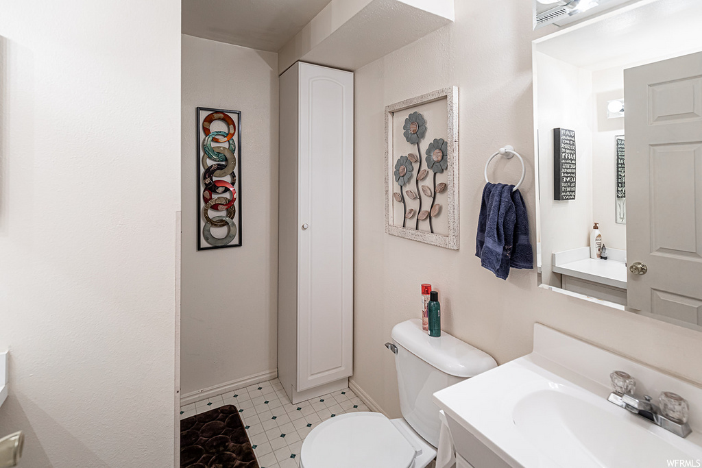 half bath with tile flooring, toilet, dual vanities, and mirror