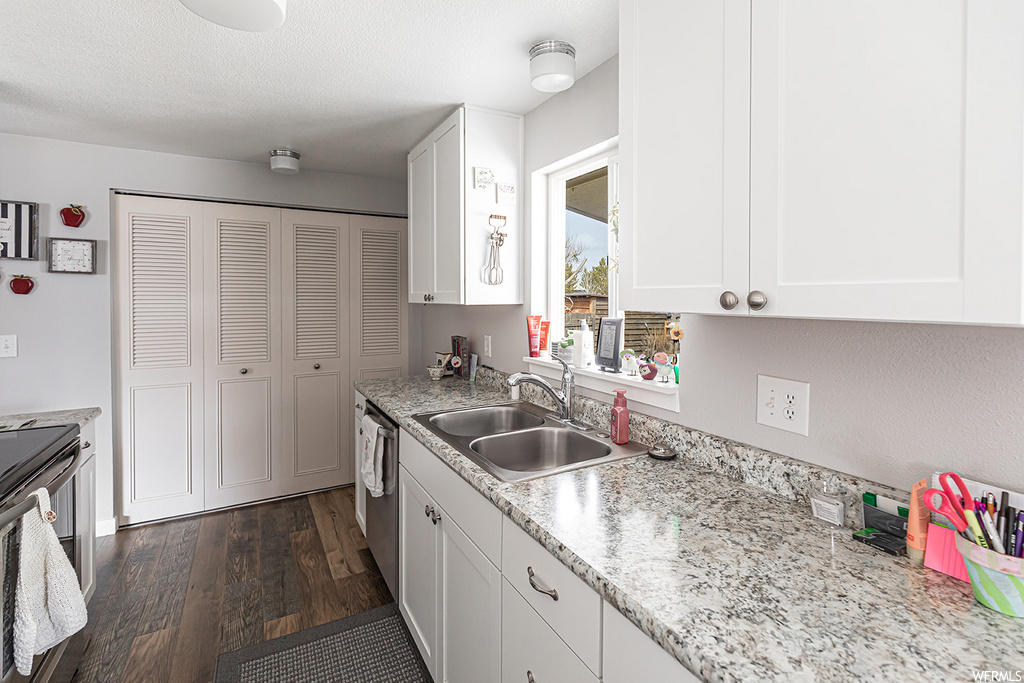 kitchen featuring hardwood floors, dishwasher, and white cabinets