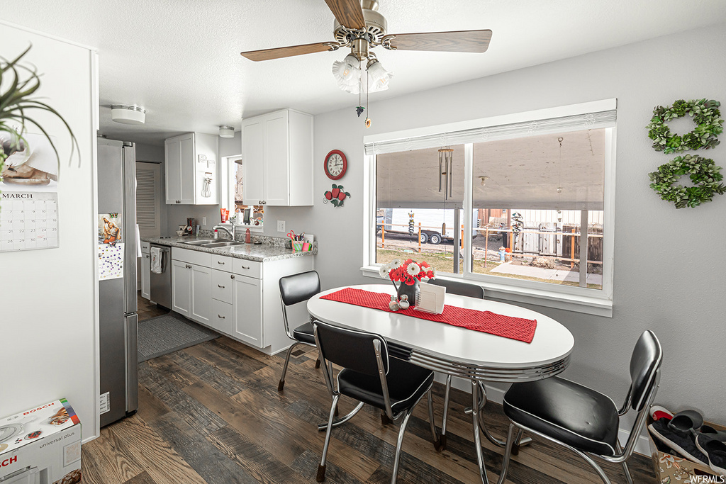 wood floored dining area featuring natural light, a ceiling fan, and stainless steel finishes