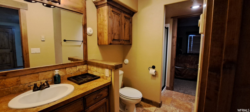 half bathroom with tile flooring, mirror, toilet, and vanity with extensive cabinet space