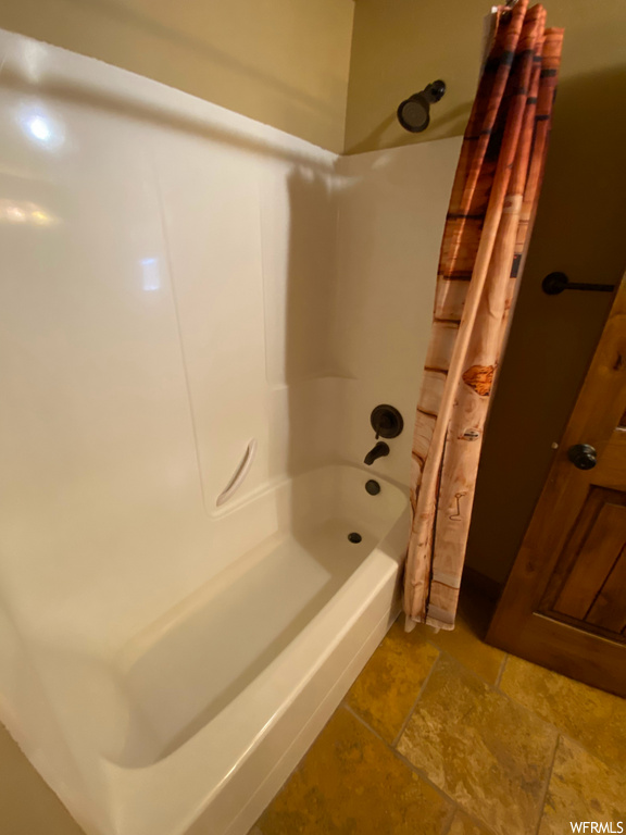 bathroom featuring tile floors, shower curtain, and washtub / shower combination