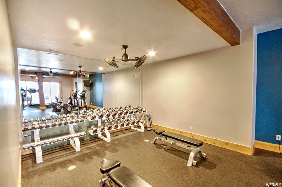 exercise room with natural light and wood beam ceiling