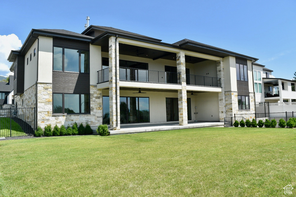 Back of property featuring a balcony and a yard