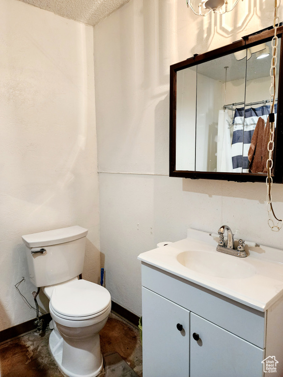 Bathroom with tile floors, a textured ceiling, vanity with extensive cabinet space, and toilet