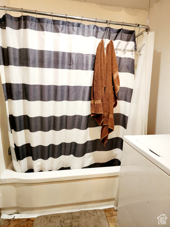 Bathroom featuring washer / dryer, tile floors, and shower / tub combo with curtain
