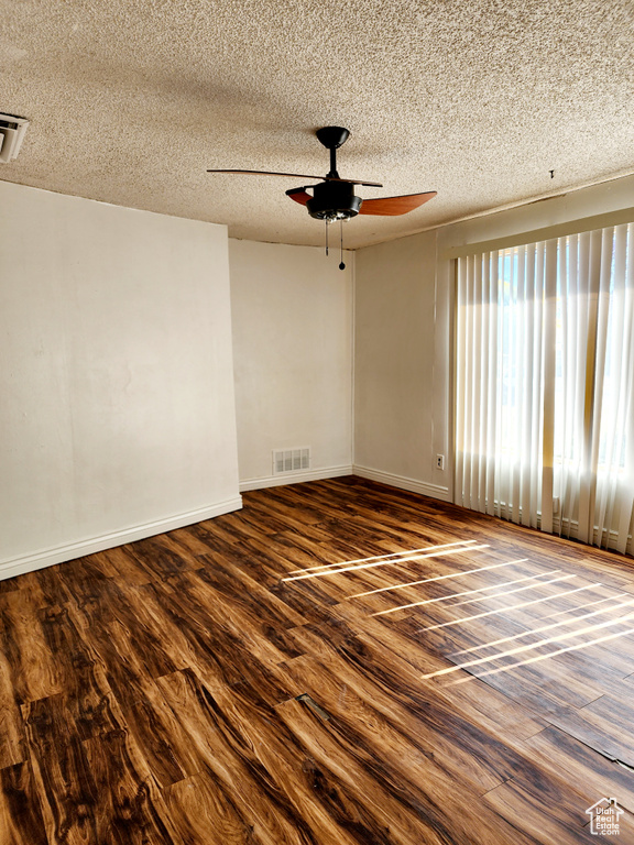 Spare room featuring dark hardwood / wood-style floors, a textured ceiling, and ceiling fan