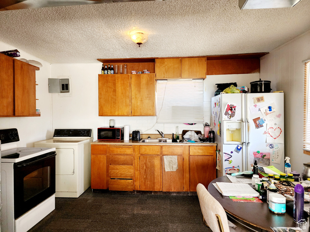 Kitchen with white appliances, washer / clothes dryer, a textured ceiling, and sink