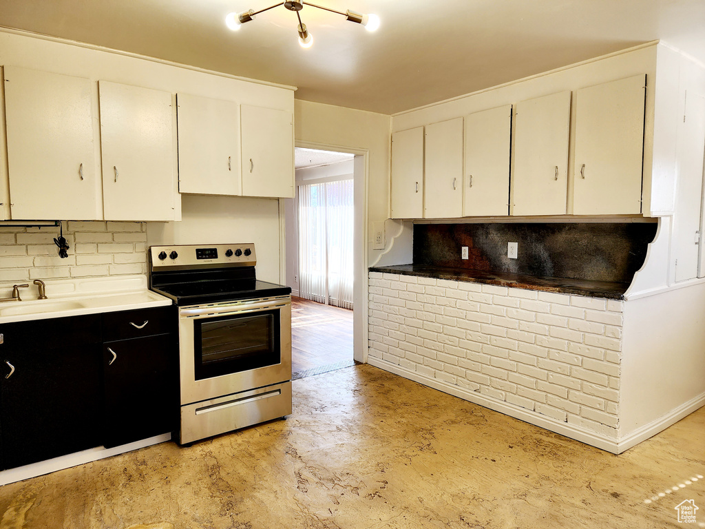 Kitchen featuring white cabinets, stainless steel electric stove, sink, and backsplash
