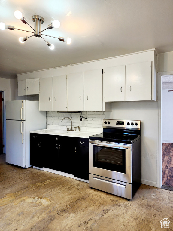 Kitchen with white fridge, backsplash, a chandelier, white cabinets, and stainless steel range with electric cooktop
