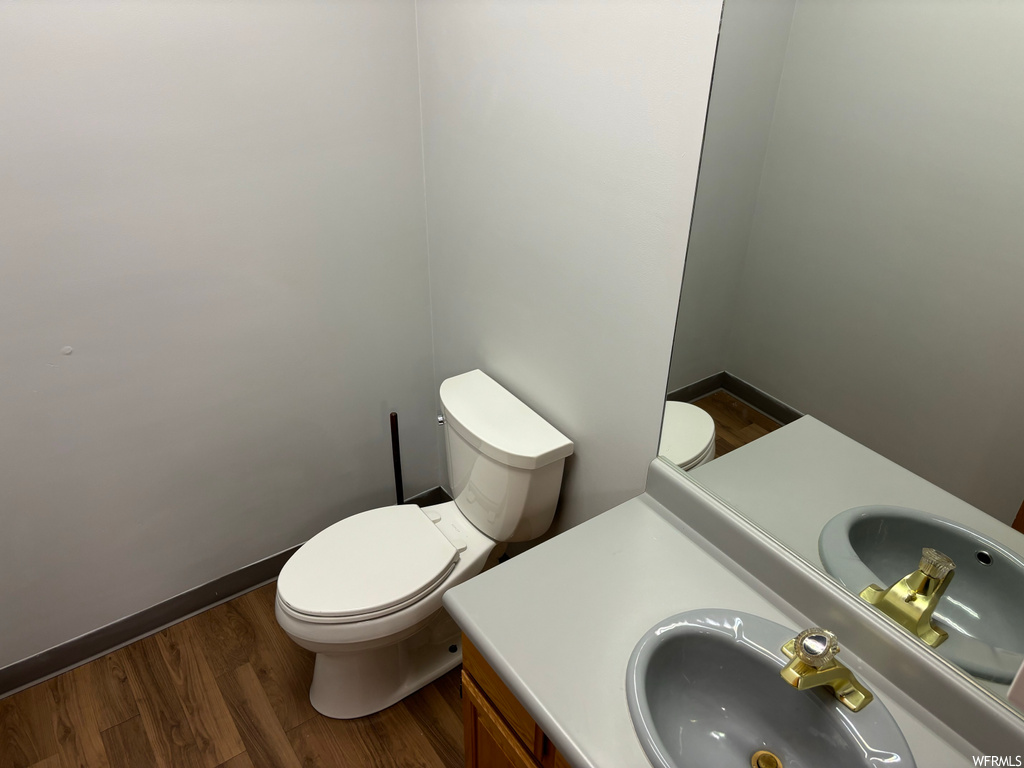 Bathroom featuring toilet, large vanity, and hardwood / wood-style floors