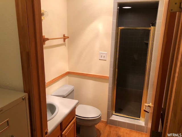 full bathroom featuring shower with shower door, toilet, and vanity