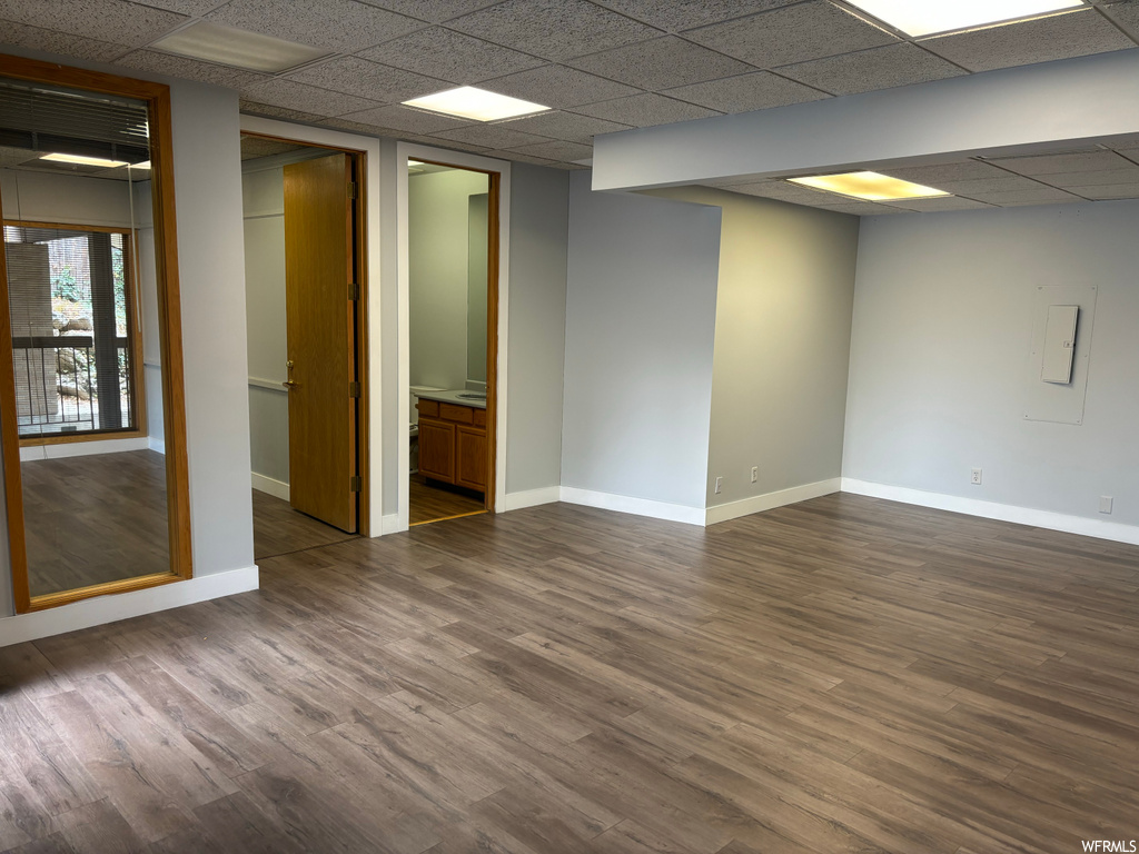 Unfurnished room featuring dark hardwood / wood-style flooring and a drop ceiling