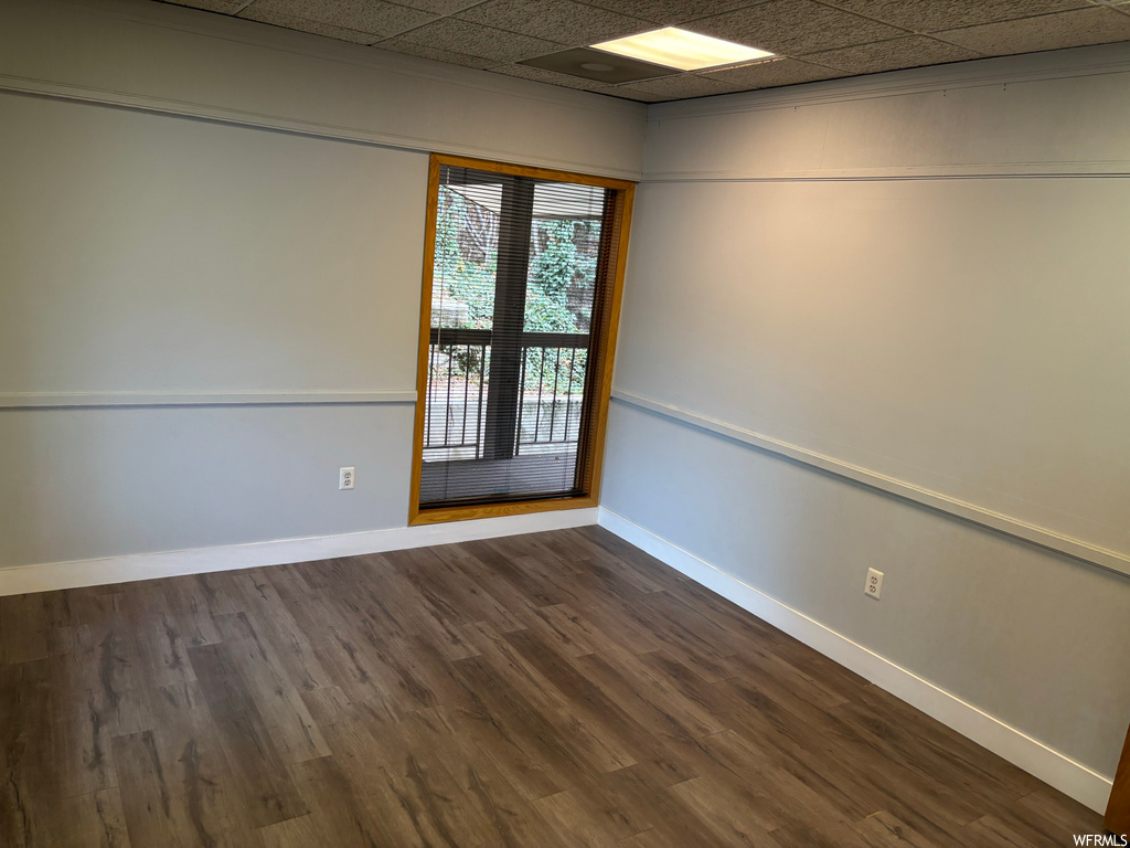 Unfurnished room featuring dark hardwood / wood-style floors and a drop ceiling