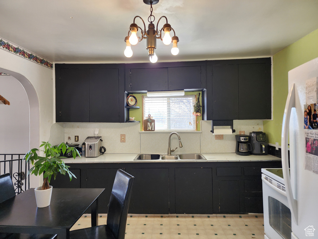 Kitchen featuring sink, light tile flooring, an inviting chandelier, tasteful backsplash, and white range