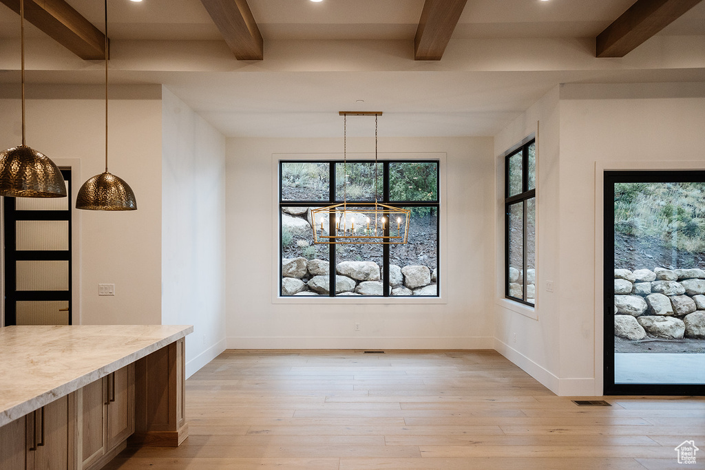Unfurnished dining area featuring beam ceiling, a chandelier, and light wood-type flooring