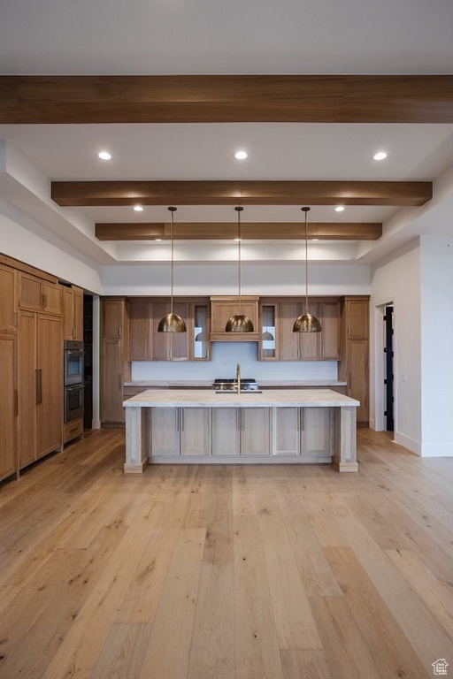 Kitchen with a kitchen bar, hanging light fixtures, stainless steel double oven, and light hardwood / wood-style flooring