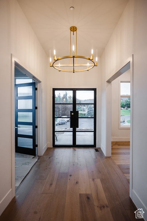 Doorway to outside with dark hardwood / wood-style floors, a chandelier, and french doors