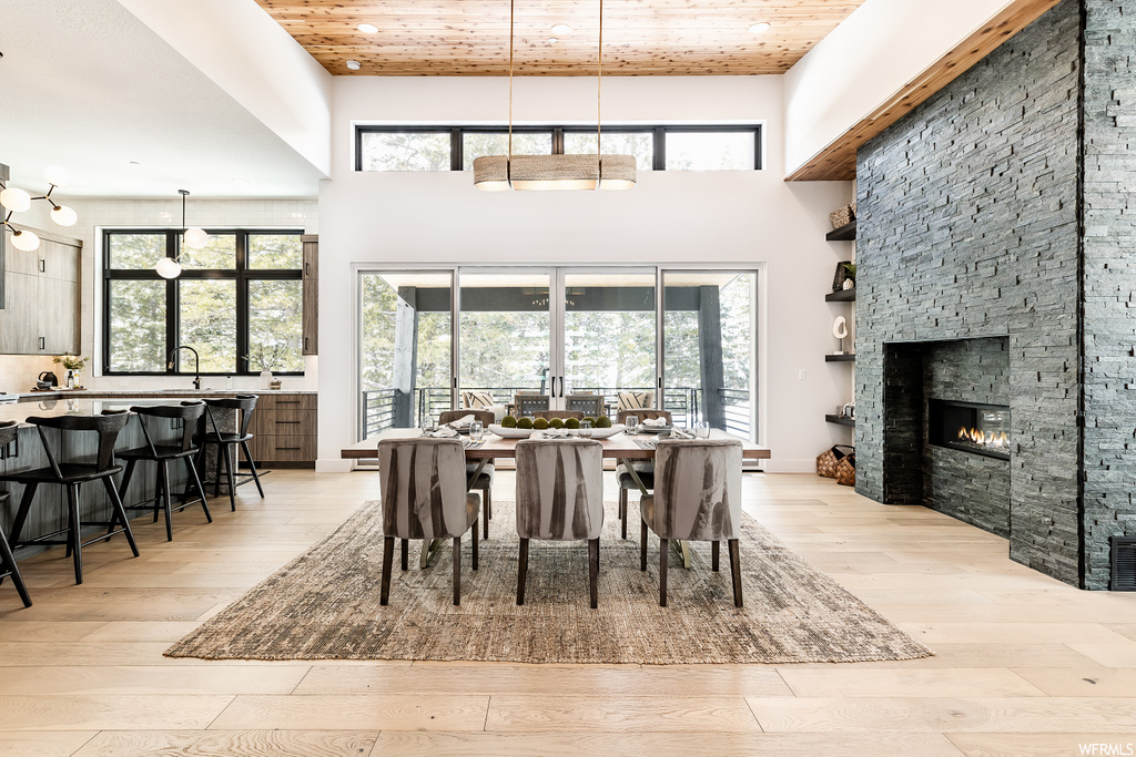 hardwood floored dining area with natural light, a kitchen bar, and a fireplace