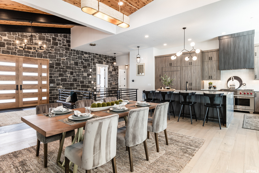 dining room featuring a kitchen bar, hardwood flooring, exposed bricks, and stainless steel finishes