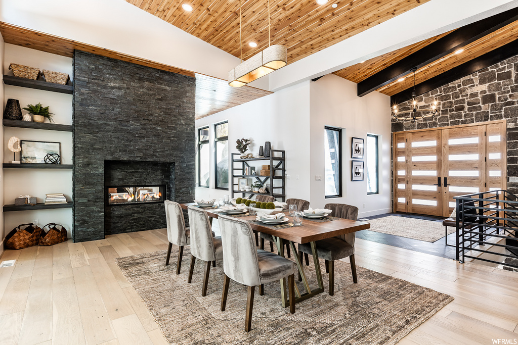 hardwood floored dining space with wood beam ceiling and a fireplace