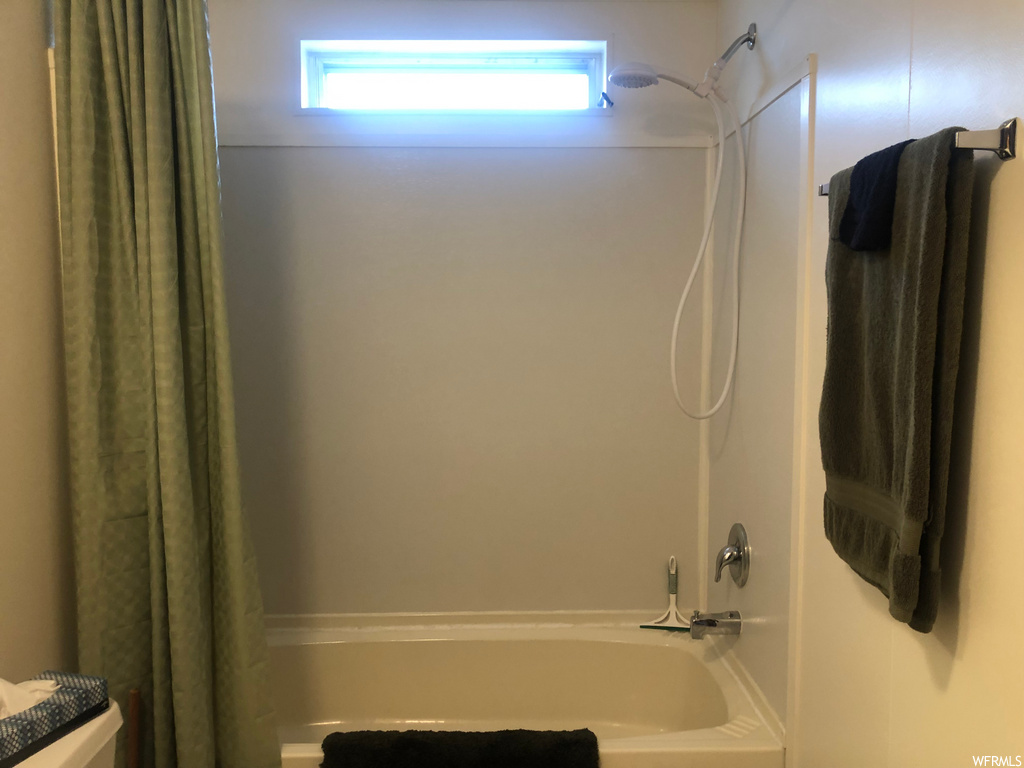 bathroom featuring shower curtain, toilet, and bathtub / shower combination