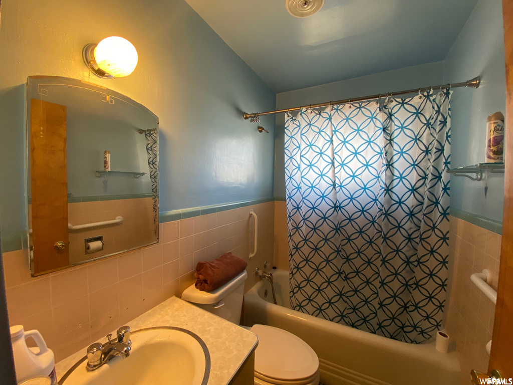 full bathroom featuring toilet, shower curtain, mirror, shower / bath combination, and vanity