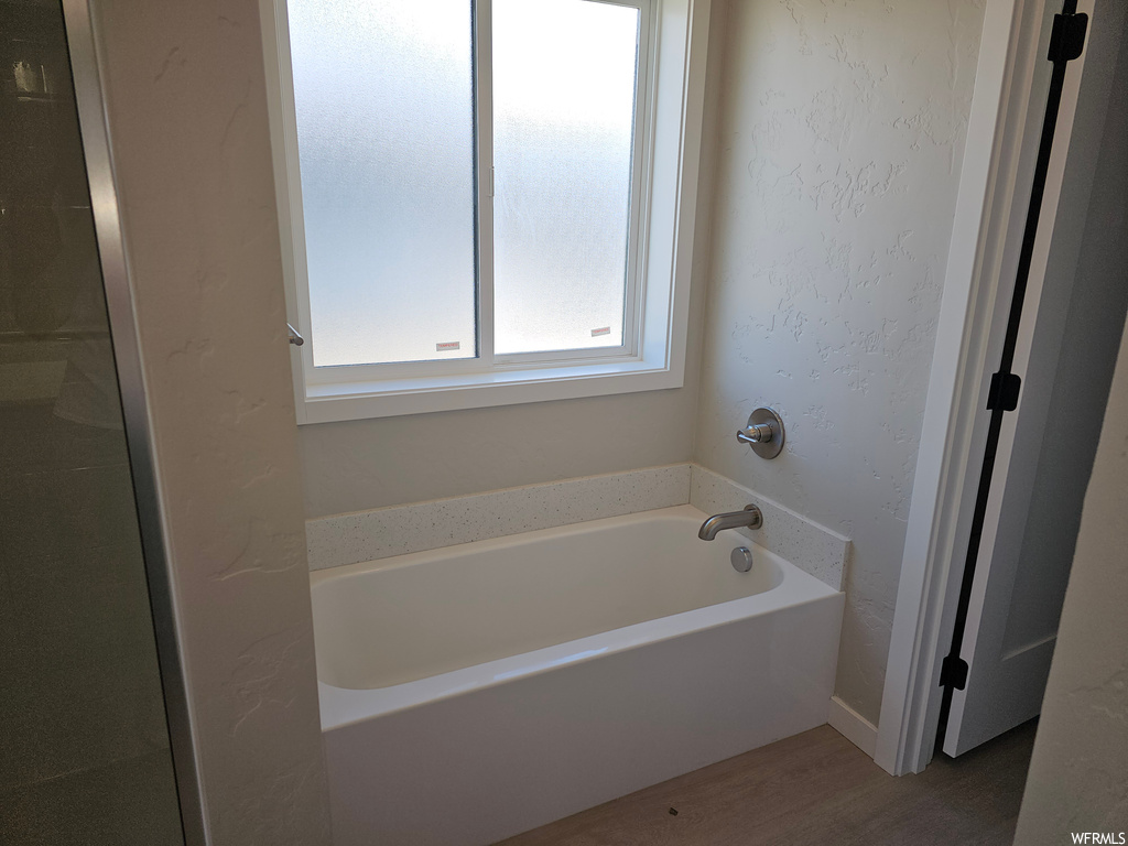 Bathroom featuring dark hardwood floors and a tub