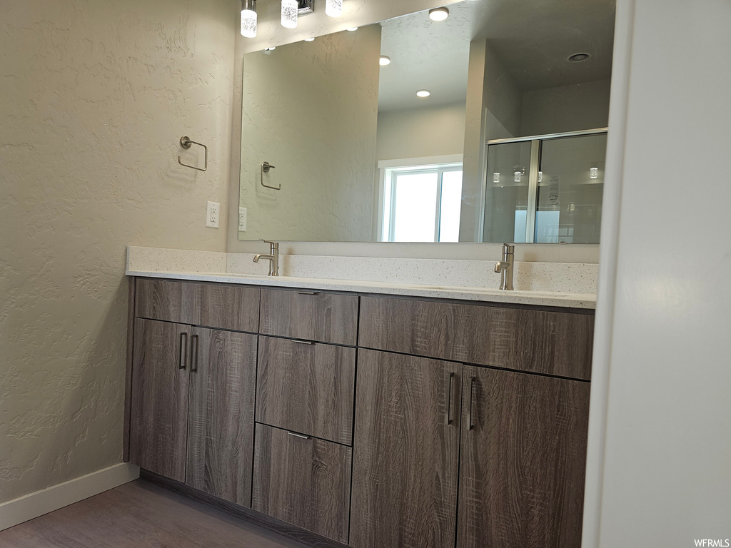 Bathroom featuring hardwood floors, large vanity, and mirror