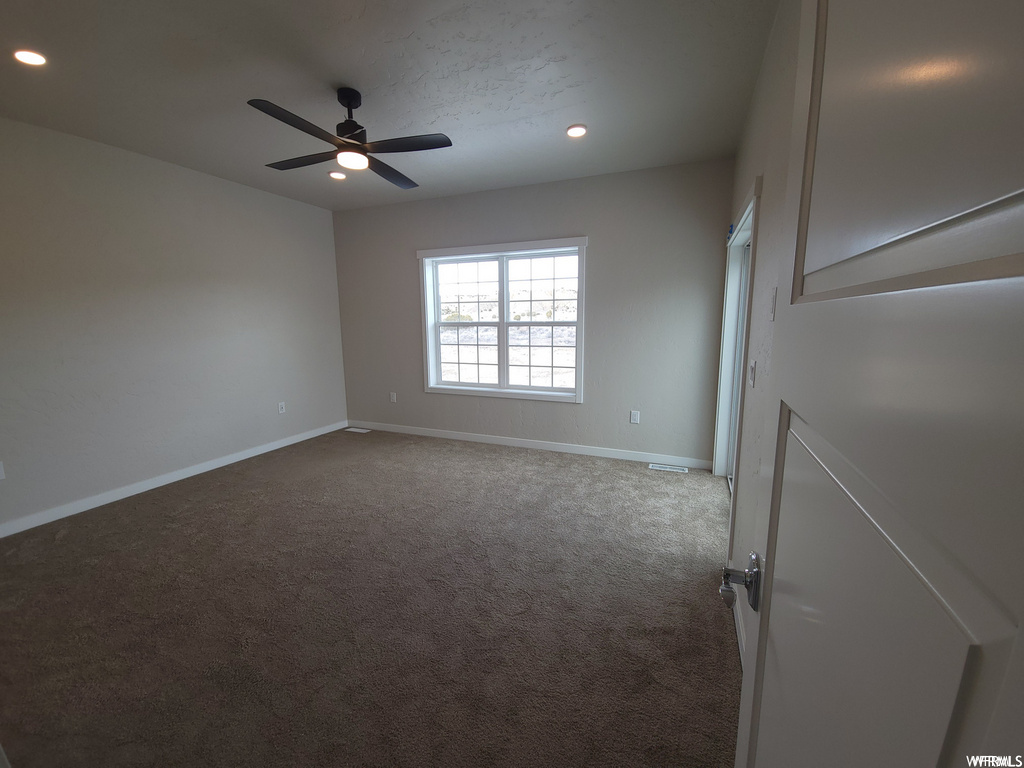 Spare room with a ceiling fan, carpet, and natural light