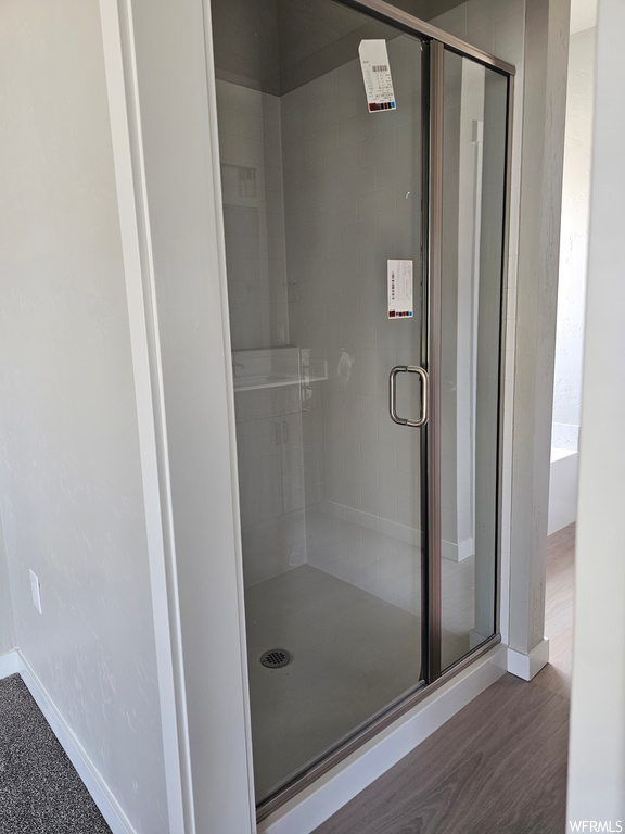 Bathroom with a shower with door and hardwood flooring