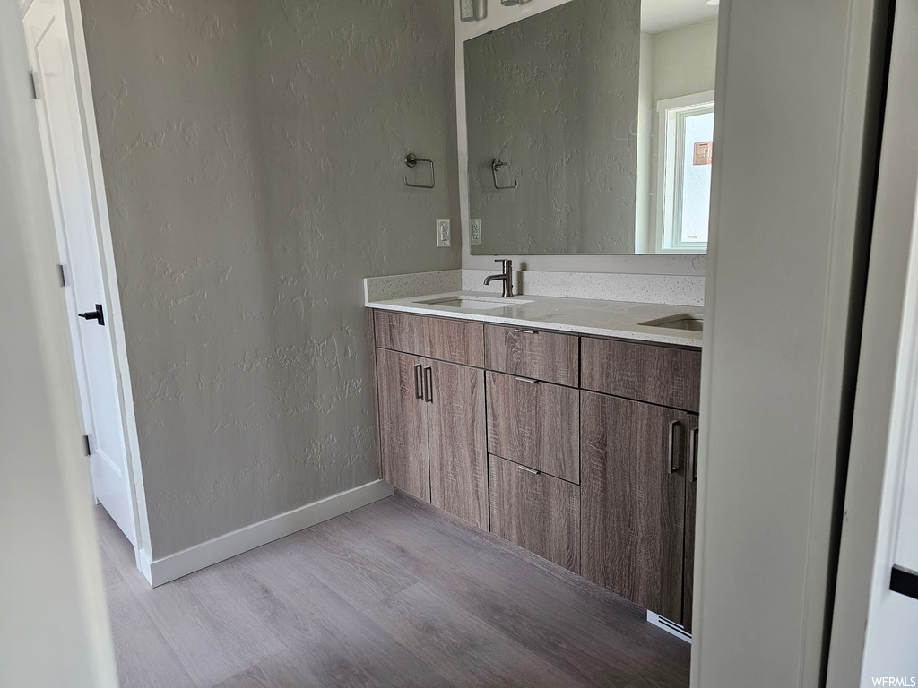 Bathroom featuring mirror, dual bowl vanity, and light parquet floors