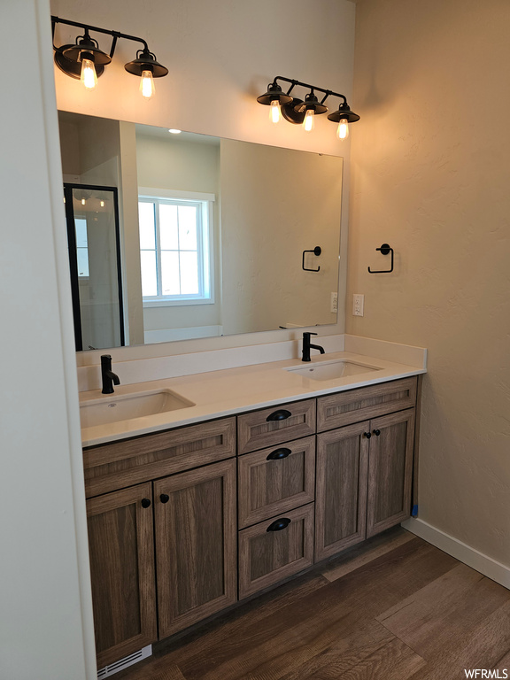 Bathroom with double vanity, mirror, and hardwood floors