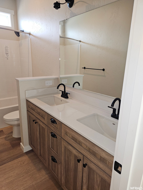 Full bathroom with shower / washtub combination, mirror, wood-type flooring, and dual vanity