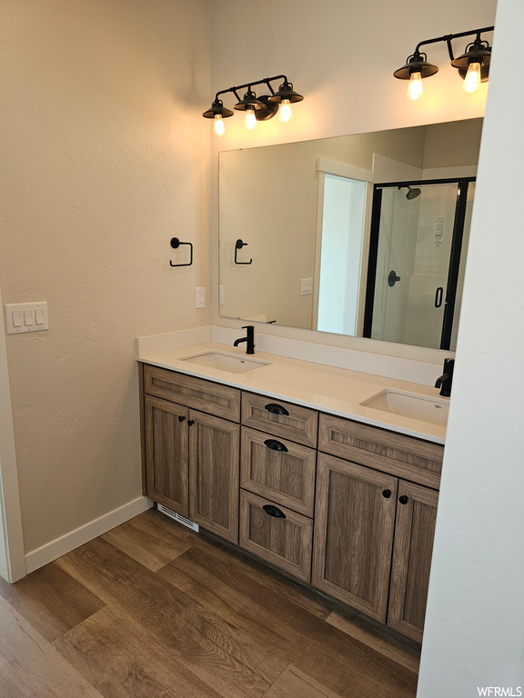 Bathroom with a shower with door, wood-type flooring, mirror, and dual large bowl vanity