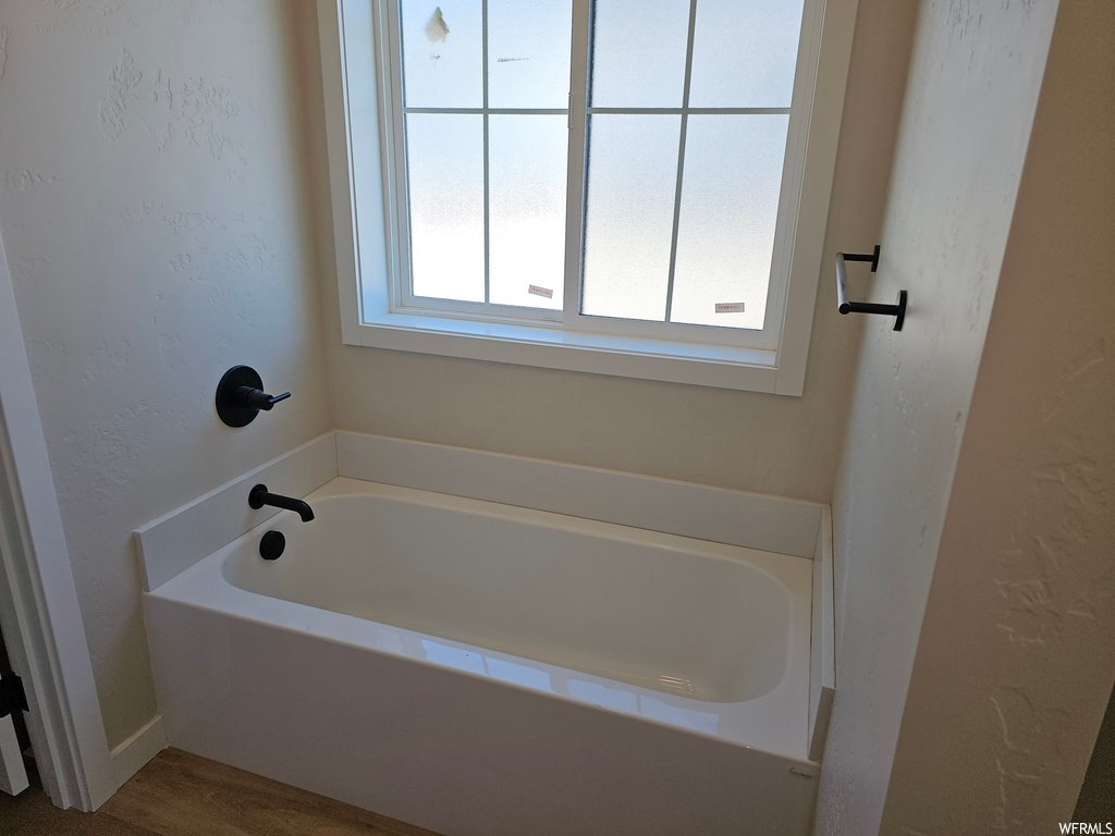 Bathroom with a bathtub, wood-type flooring, and a wealth of natural light