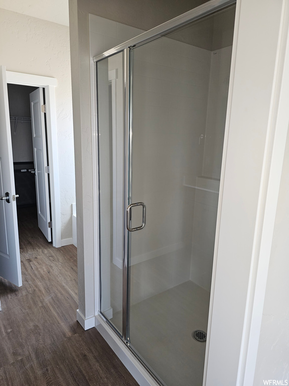 Bathroom featuring dark hardwood flooring and a shower with shower door
