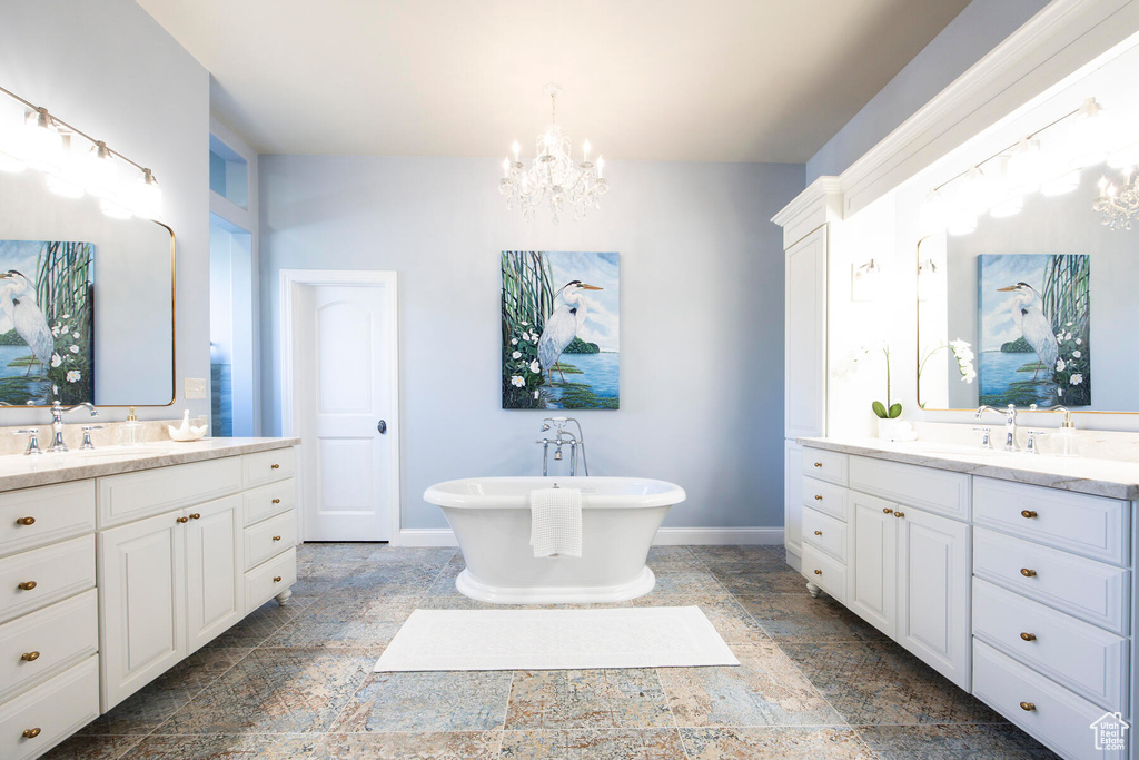 Bathroom with an inviting chandelier, dual vanity, tile floors, and a bath