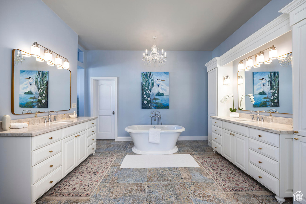 Bathroom with an inviting chandelier, dual vanity, a tub, and tile flooring