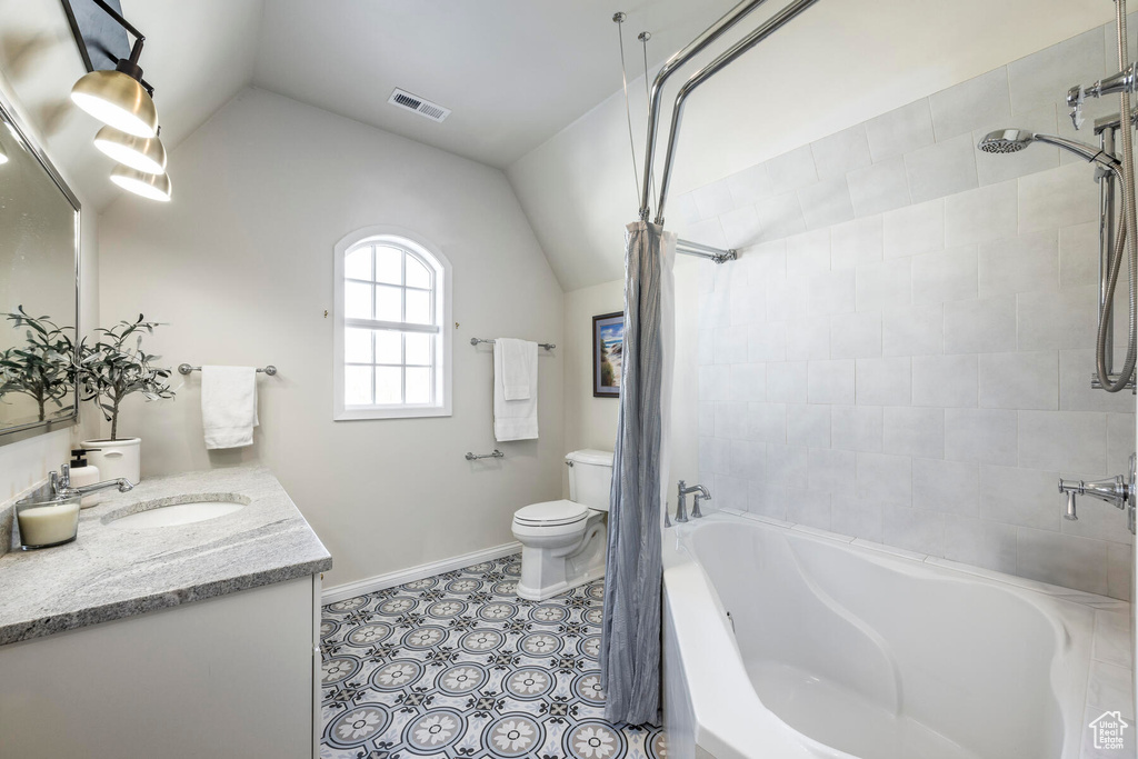 Full bathroom featuring tiled shower / bath combo, vanity, lofted ceiling, and toilet