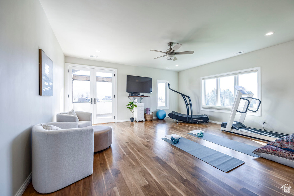 Exercise room with a baseboard heating unit, dark hardwood / wood-style flooring, french doors, and ceiling fan