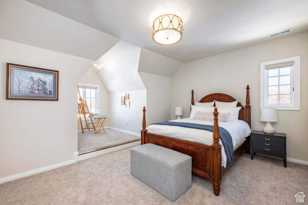 Bedroom featuring light carpet, multiple windows, and vaulted ceiling