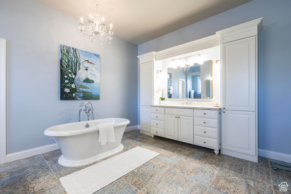Bathroom featuring oversized vanity, a washtub, a chandelier, and tile flooring